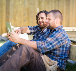 Image showing Carpenter Holding Digital Tablet While Coworker Pointing At It