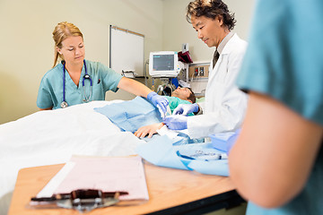 Image showing Nurse Assisting Doctor In Stitching Wound On Patient's Hand