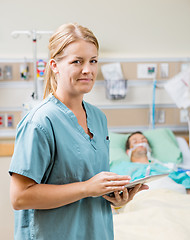 Image showing Nurse Holding Digital Tablet With Patient Resting In Hospital