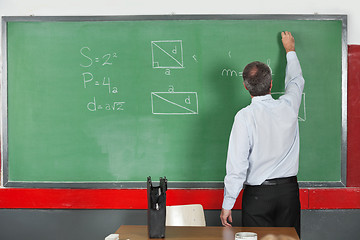 Image showing Male Teacher Writing On Greenboard In Classroom