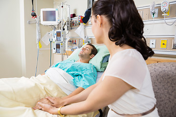 Image showing Woman Holding Man's Hand Lying On Bed