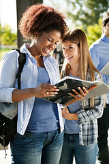 Image showing Student Holding Book While Friend Looking At Her In Campus