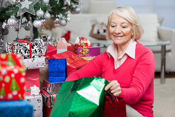 Image showing Woman Looking In Bag While Sitting By Christmas Gifts