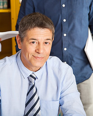 Image showing Confident Teacher Smiling With Student Standing In Background At