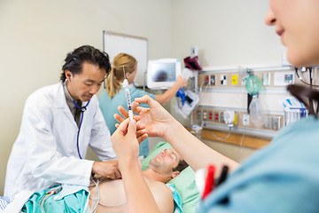 Image showing Nurse Preparing Injection While Doctor And Colleague Examining P