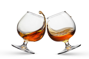 Image showing Splash of cognac in two glasses isolated on white background