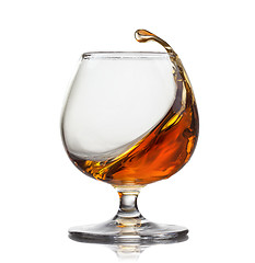 Image showing Splash of cognac in glass isolated on white background