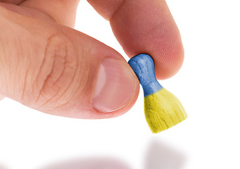 Image showing Hand holding wooden pawn, flag painting, selective focus