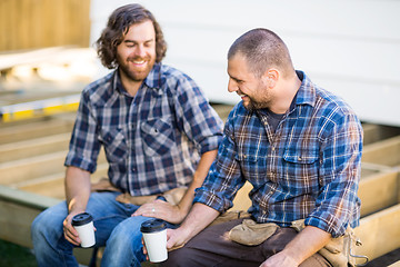 Image showing Construction Workers Holding Disposable Coffee Cups On Wooden Fr