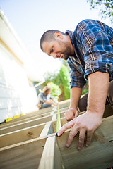 Image showing Carpenter Measuring Wood With Tape While Coworker Assisting Him