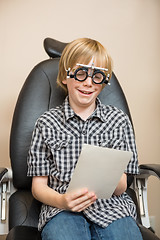 Image showing Boy With Trial Frame Reading Test Chart On Chair