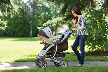 Image showing Woman Looking Into Baby Carriage In Park