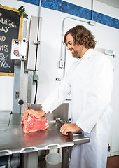 Image showing Smiling Butcher Slicing Meat In Machine