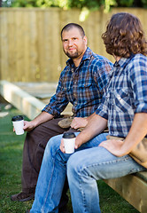 Image showing Confident Worker Holding Disposable Cup While Sitting With Cowor