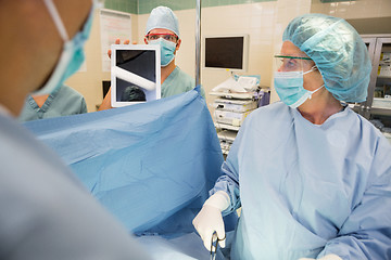 Image showing Nurse Showing Digital Tablet To Surgeons During Surgery