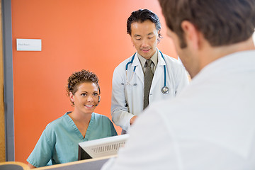 Image showing Nurse Looking At Patient With Doctor Standing By In Hospital