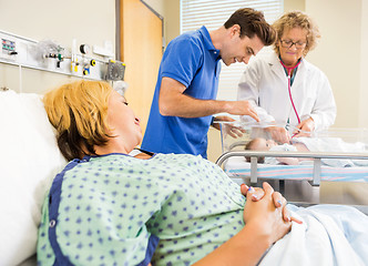 Image showing Mature Doctor Examining Newborn Babygirl While Parents Looking A