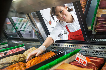 Image showing Saleswoman Picking Meat Displayed In Cabinet