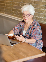 Image showing Woman Text Messaging Through Smartphone In Cafe