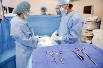 Image showing Surgical Tools On Stand With Doctors Operating Patient