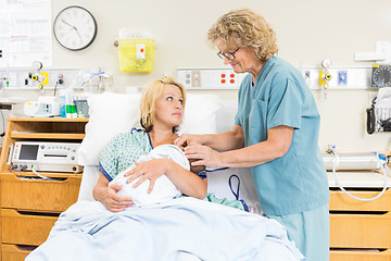 Image showing Smiling Nurse Assisting Woman In Breast Feeding Baby In Hospital