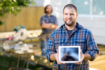 Image showing Carpenter Displaying Digital Tablet With Coworker In Background