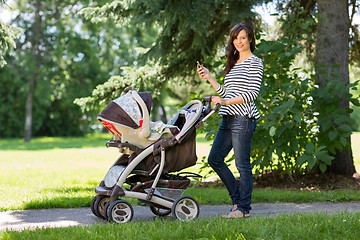 Image showing Mother With Cell Phone And Carriage Walking In Park