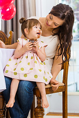 Image showing Mother Looking At Birthday Girl Eating Cupcake