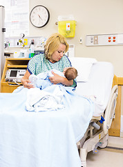 Image showing Mother Looking At Newborn Baby While Sitting In Hospital Bed