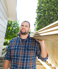 Image showing Carpenter Carrying Planks On Shoulder At Construction Site