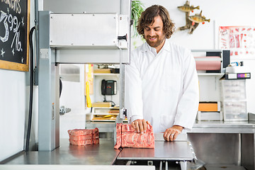 Image showing Smiling Butcher Slicing Meat In Machine