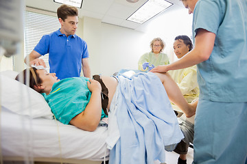 Image showing Man Looking At Doctor Delivering Baby