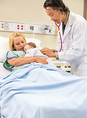 Image showing Doctor Examining Babygirl Sleeping In Mother's Arms