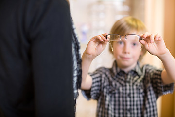 Image showing Boy Holding Spectacles With Mother In Foreground At Shop