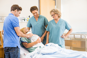 Image showing Nurses And Man Looking At Newborn Baby Sleeping On Mother