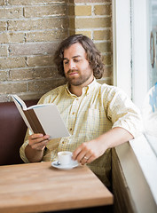 Image showing Man With Coffee Cup Reading Book In Cafe