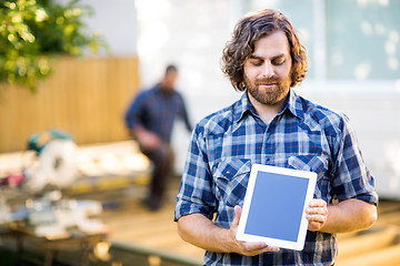 Image showing Carpenter Displaying Digital Tablet With Coworker Working In Bac