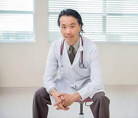 Image showing Doctor Sitting At Hospital Room With Patient In Background