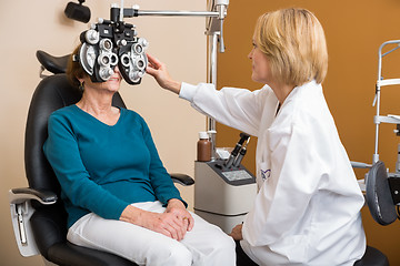 Image showing Optician Using Phoropter To Examine Woman's Eyes