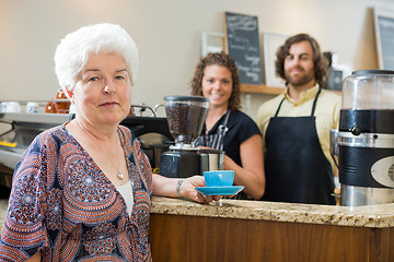 Image showing Woman Holding Coffee Cup With Workers At Counter