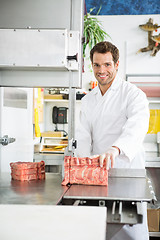 Image showing Portrait Of Butcher Slicing Meat On Bandsaw