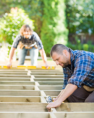 Image showing Carpenter Drilling Wood With Coworker In Background