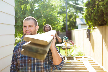 Image showing Male Carpenter And Coworker Carrying Lumbers At Construction Sit