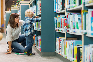 Image showing Teacher Assisting Boy In Selecting Book From Bookshelf