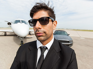 Image showing Confident Businessman In Front Of Car And Private Jet