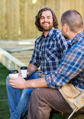 Image showing Happy Worker Holding Disposable Cup While Sitting With Coworker