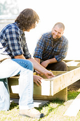 Image showing Carpenter Measuring Wooden Frame While Coworker Looking At It