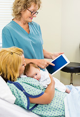 Image showing Mature Nurse Explaining Reports On Tablet To Woman With Babygirl