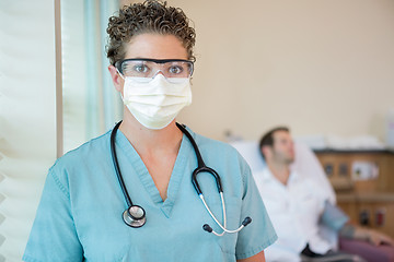 Image showing Nurse In Protective Clothing With Patient In Background