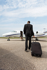 Image showing Businessman With Luggage Walking Towards Private Jet
